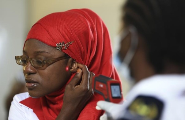 A female immigration officer uses an infrared digital laser thermometer to take the temperature of a female passenger at the Nnamdi Azikiwe International Airport in Abuja August 11, 2014. REUTERS/Afolabi Sotunde