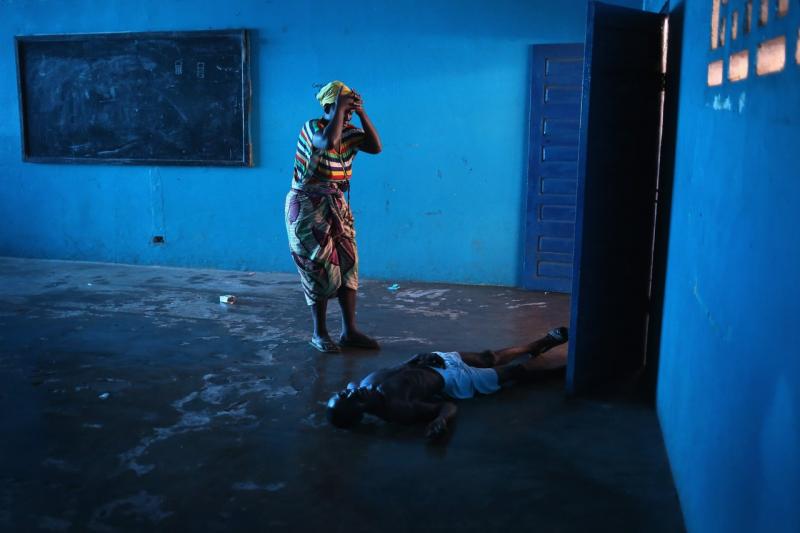 In a school building used to quarantine Ebola patients in Monrovia, Liberia, Umu Fambulle stands over her infected husband after he fell. Getty Images