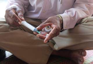 A person draws liquid from a vial into a needle.