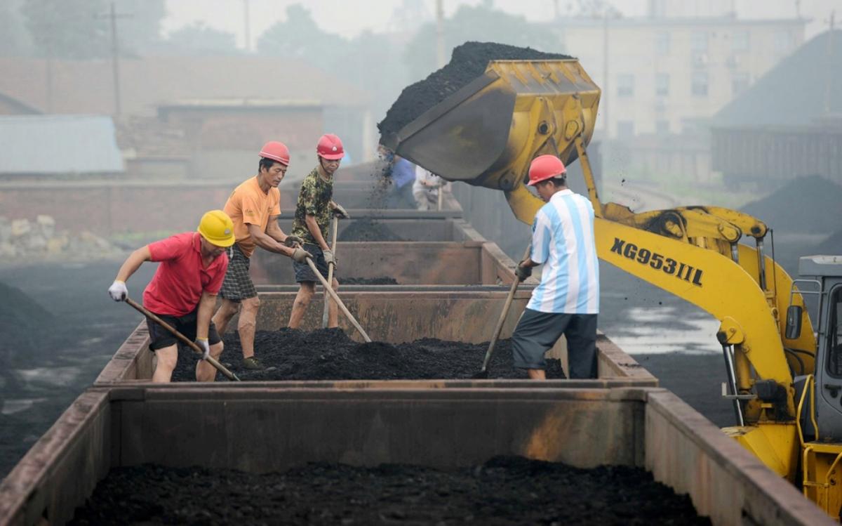 Chinese workers level coal to be used for generating electricity on a freight train at a railway station in Jiujiang city on June 16, 2014. Imaginechina via AP Images